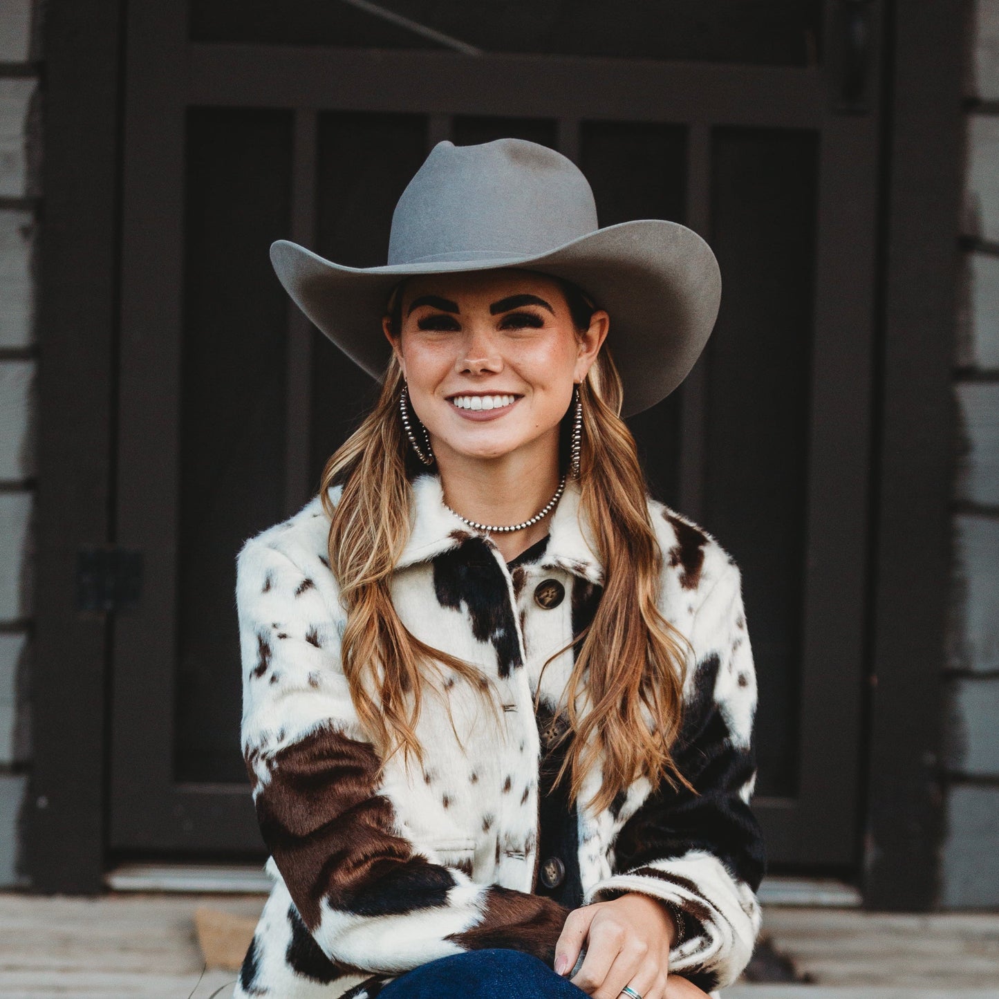 Woman in a cowboy hat sitting on steps outdoors